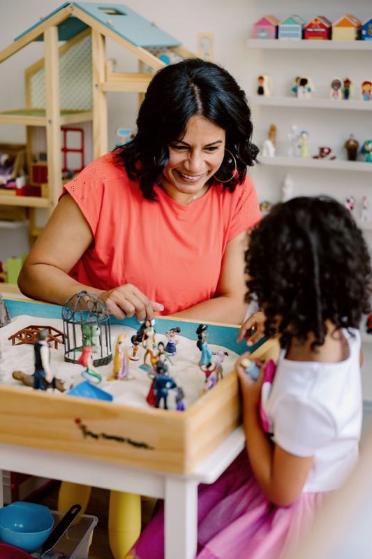 a woman and child playing with toys in a room