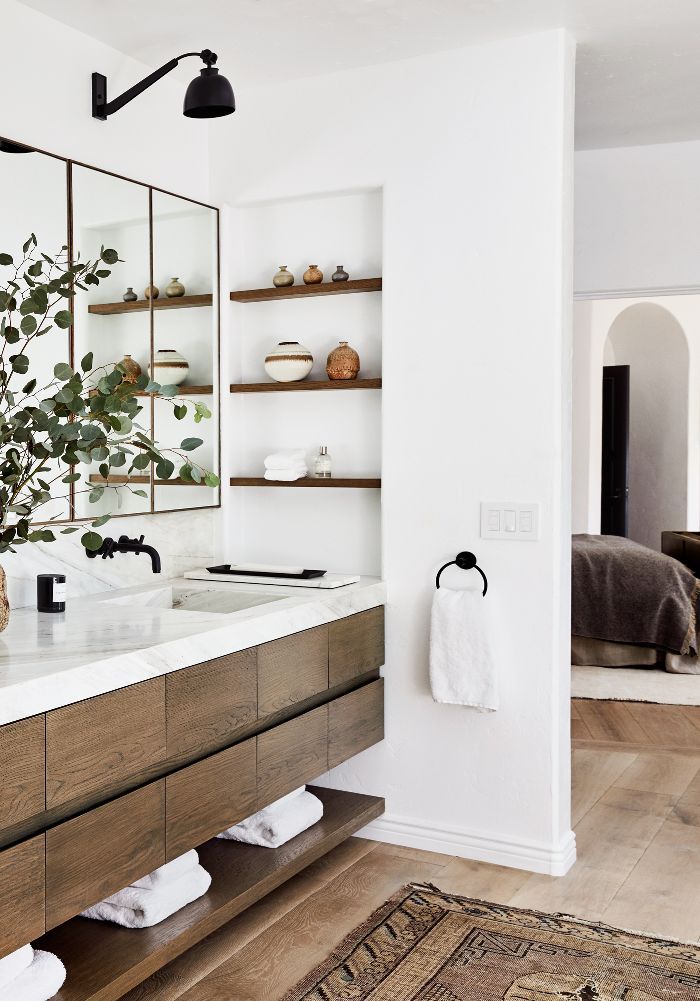 a bathroom with two sinks, mirrors and plants on the counter top in front of it