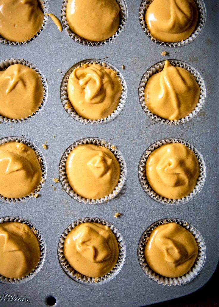 twelve cupcakes with peanut butter frosting in a muffin tin, ready to be baked