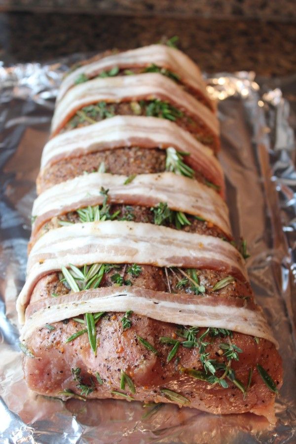 meatloaf wrapped in herbs and sliced into strips on aluminum foil, ready to be baked