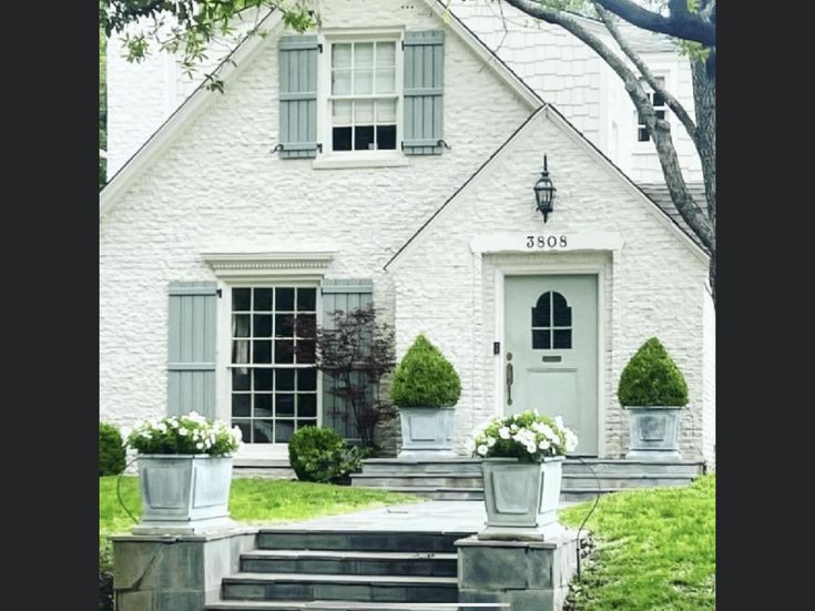 a white house with two planters on the steps