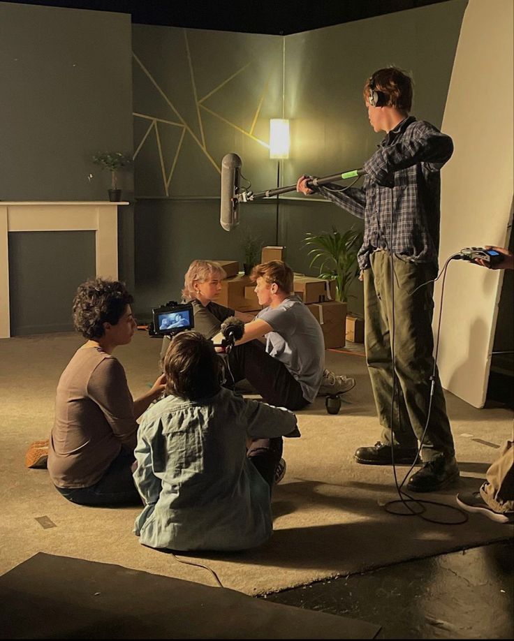 a group of people sitting on the floor in front of a man holding a video camera