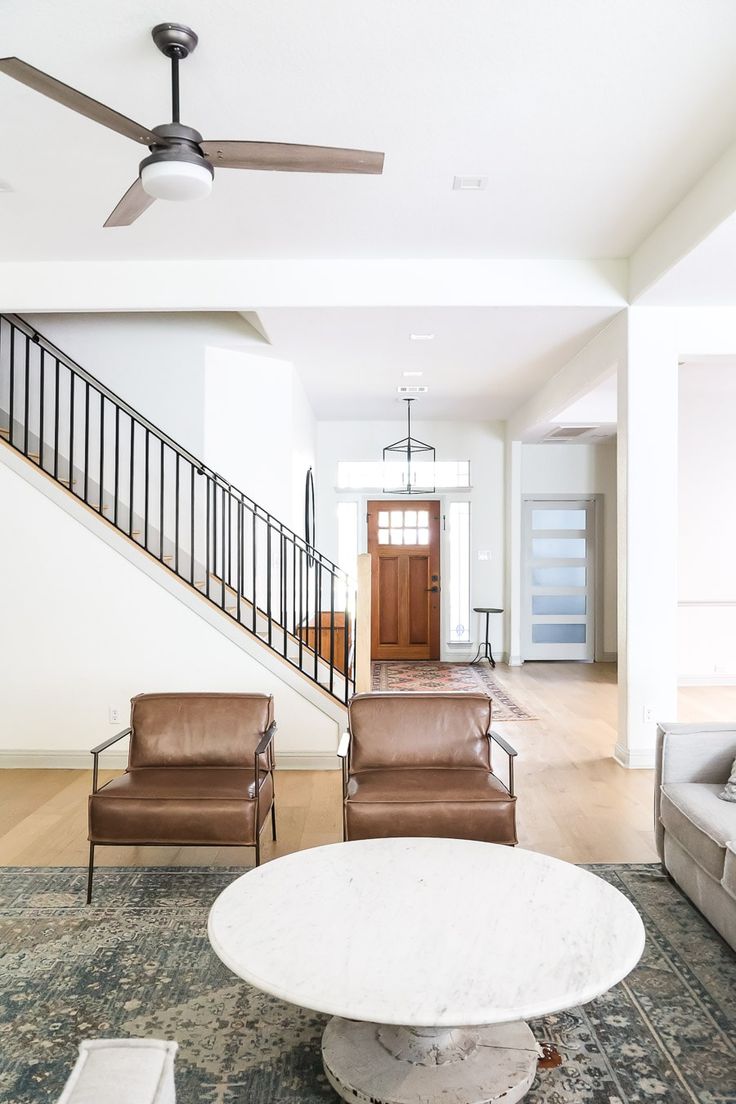 a living room filled with furniture and a white table in front of a stair case