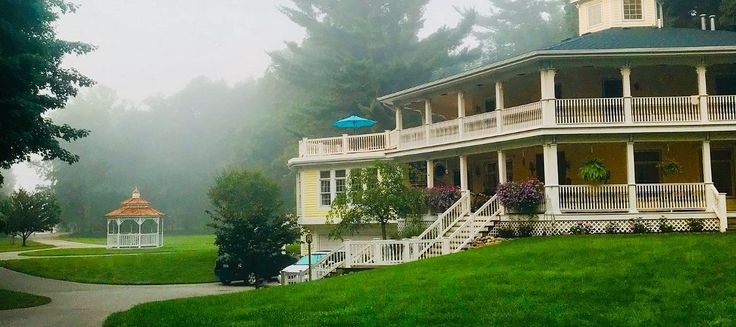 a large house sitting in the middle of a lush green field on a foggy day