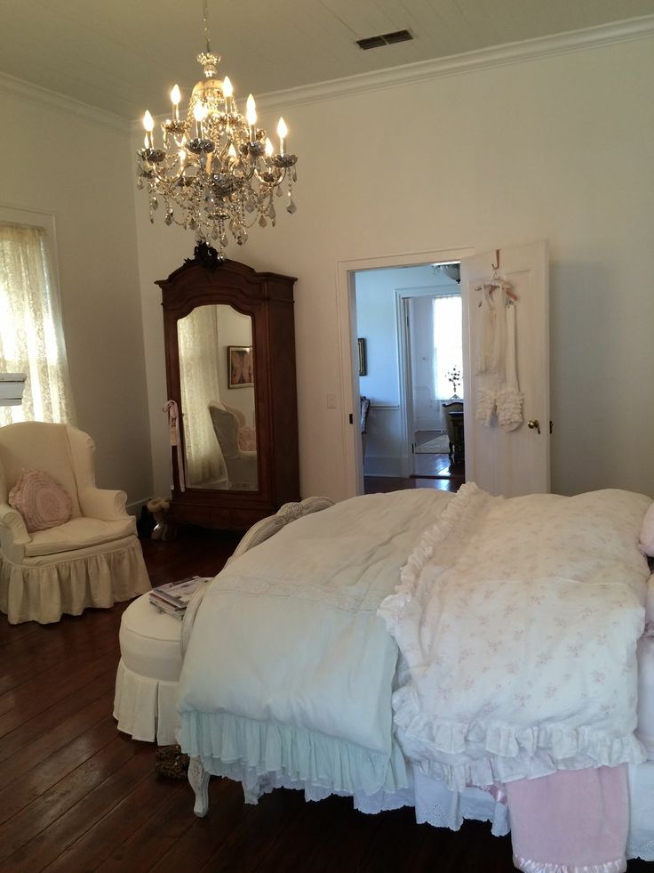 a white bed sitting in a bedroom on top of a hard wood floor