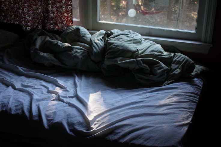 an unmade bed sitting in front of a window