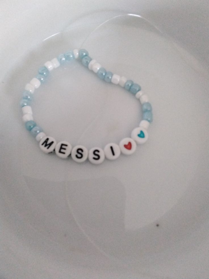 a beaded bracelet with the word mess spelled in small letters on it, sitting on top of a white plate