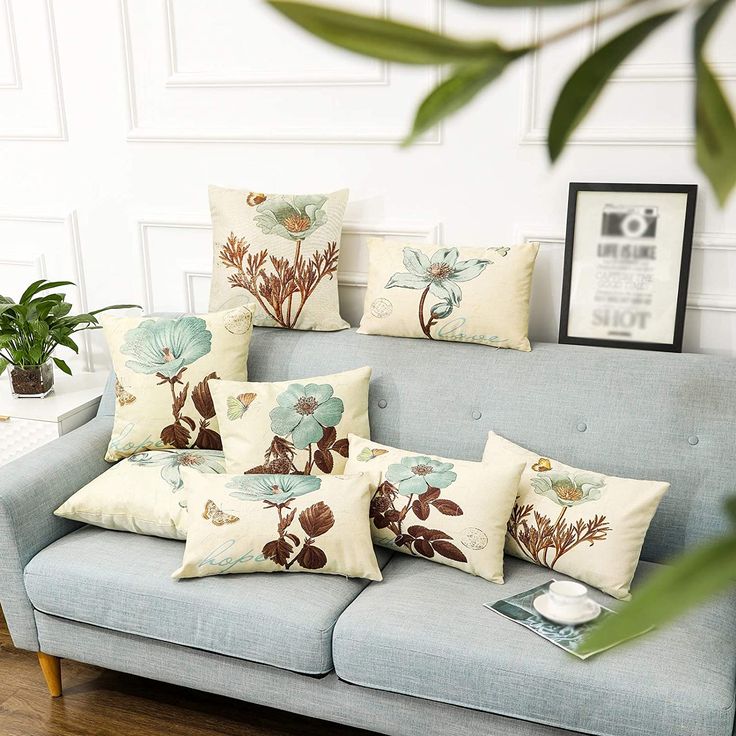 a blue couch with some pillows on top of it and a plant in the corner