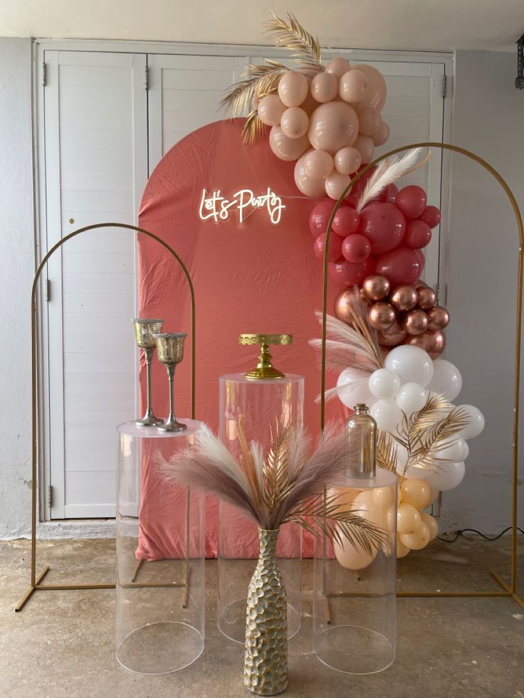 balloons and decorations on display in front of a pink backdrop