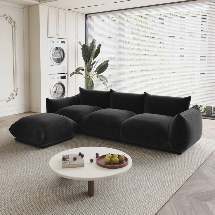 a living room with a black couch and white coffee table in front of a large window