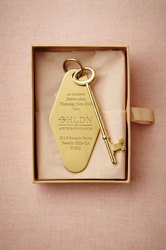 a gold key is in a box on a pink surface