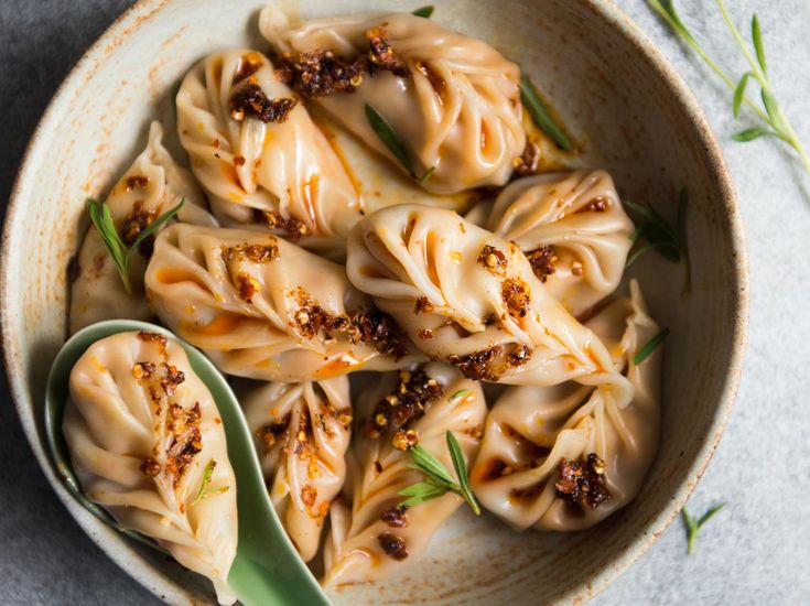 a bowl filled with dumplings next to a spoon