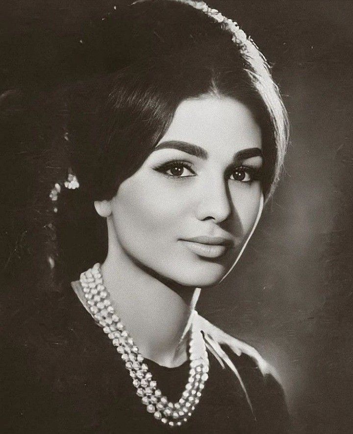 an old black and white photo of a woman wearing pearls