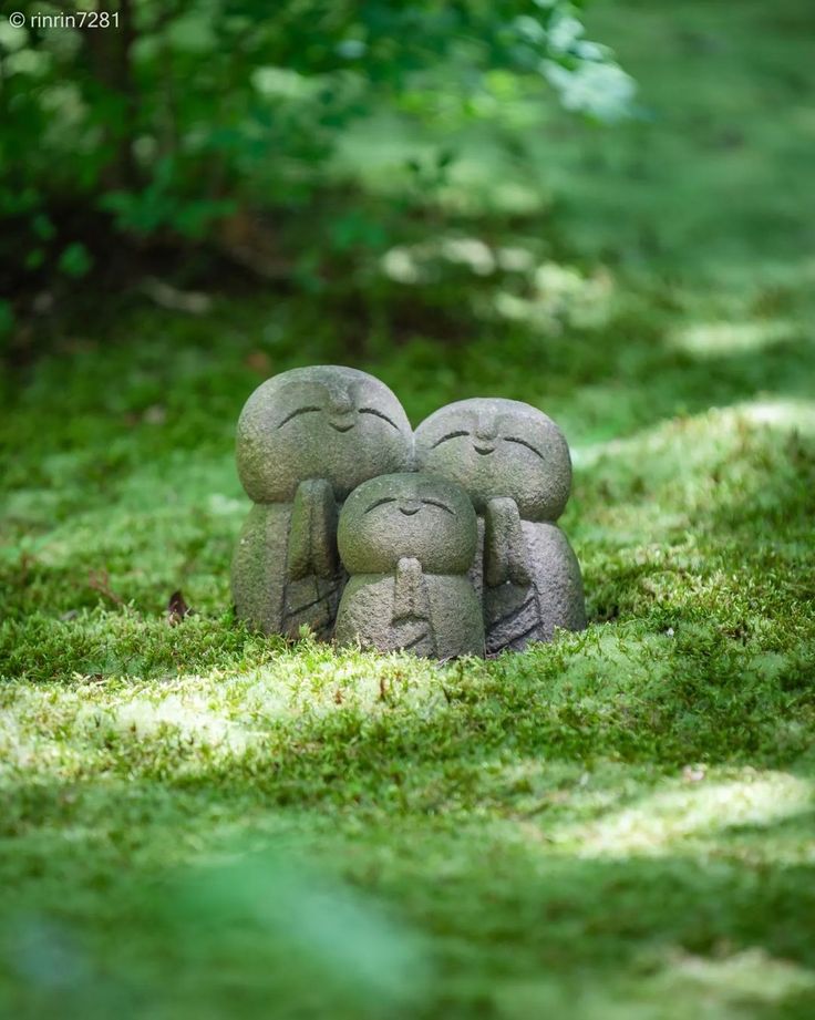 two little statues sitting in the grass