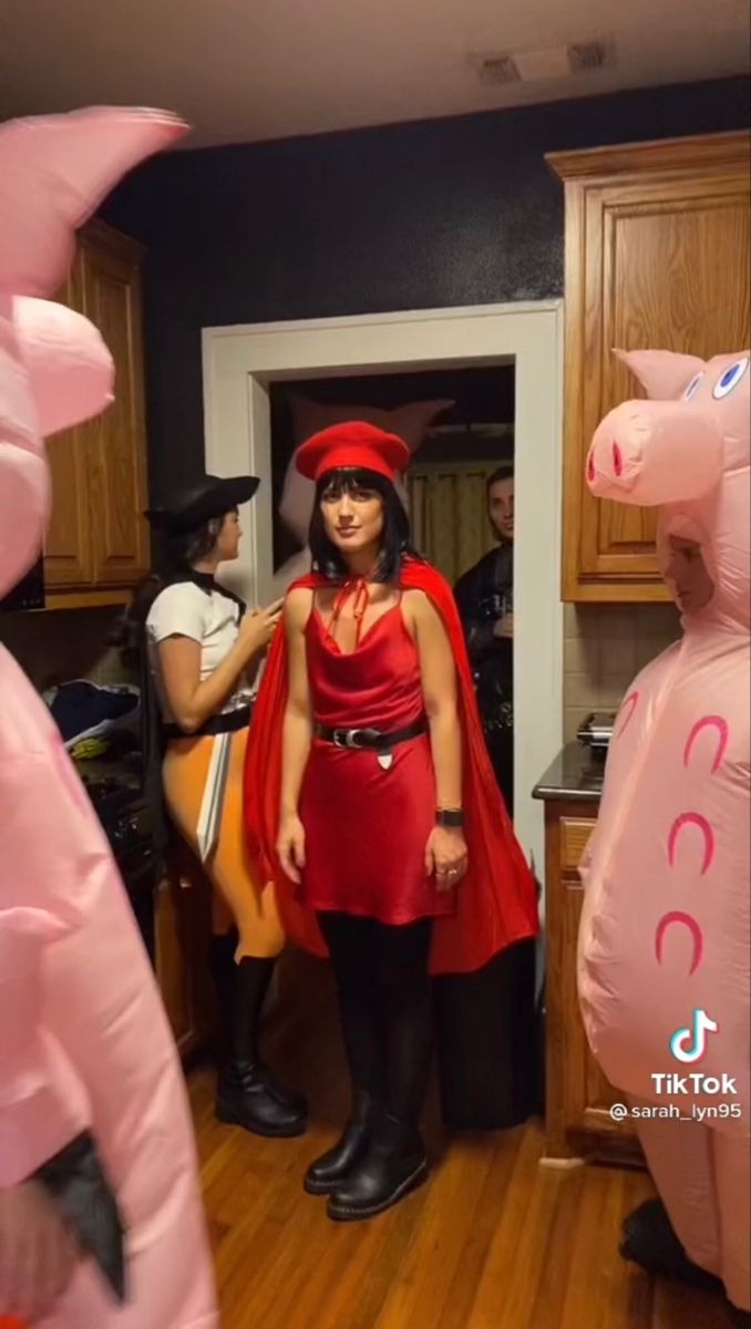 two people dressed up as pink pigs and one is wearing a red cape with horns