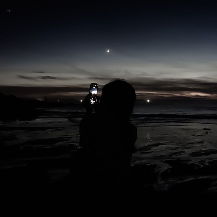 a person is taking a photo at night on the beach