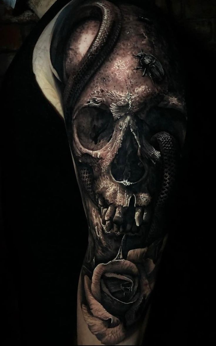 a man's half sleeve with a skull and snake on the left side of his arm