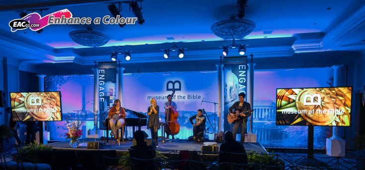 a group of people standing on top of a stage in front of tvs with musical instruments