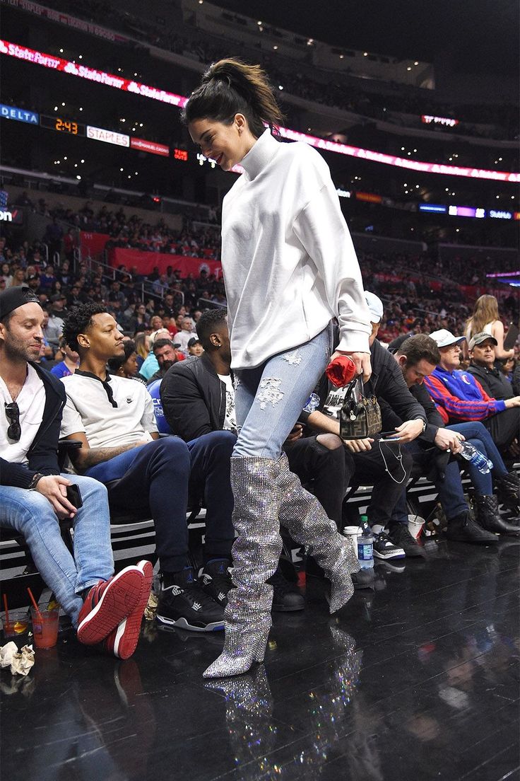 a woman is walking down the runway at a basketball game wearing boots and leggings