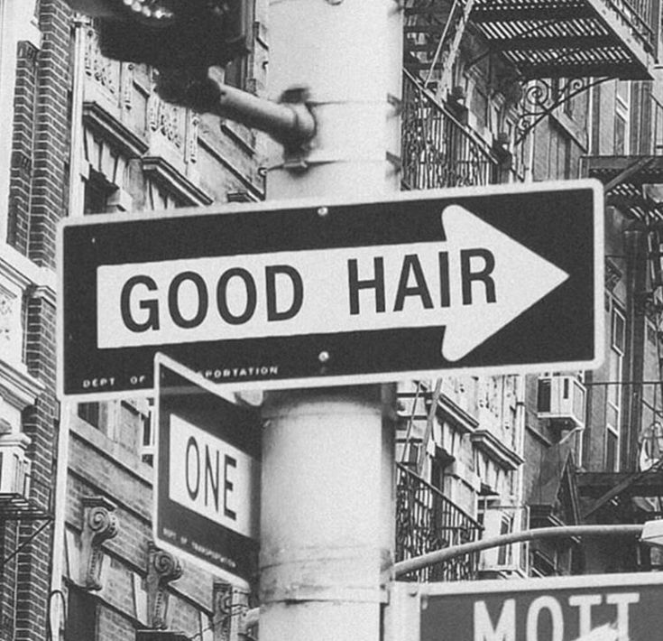 black and white photograph of street signs in new york city, with the words good hair on it