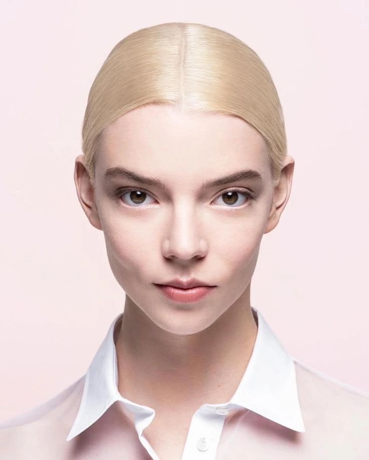 a woman with blonde hair and blue eyes is wearing a white shirt over a pink background