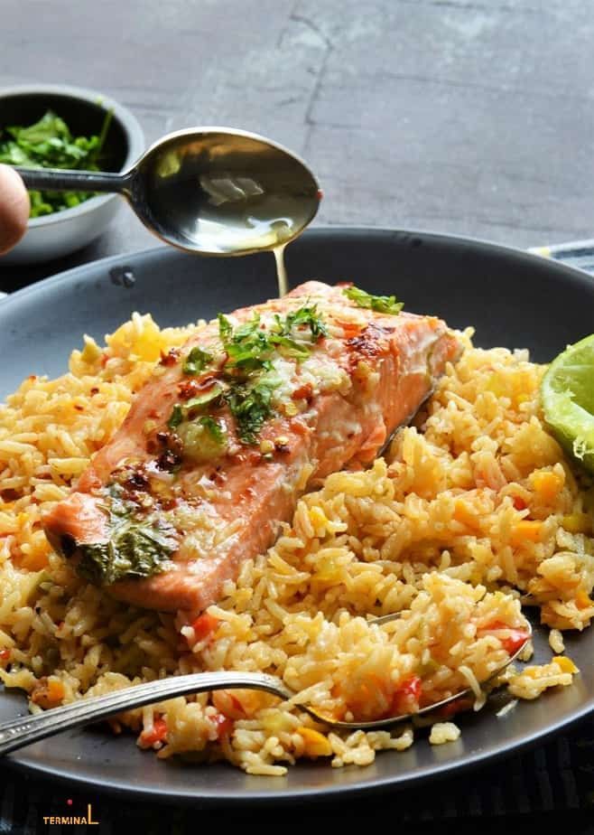 a plate with rice, meat and vegetables is being drizzled with sauce