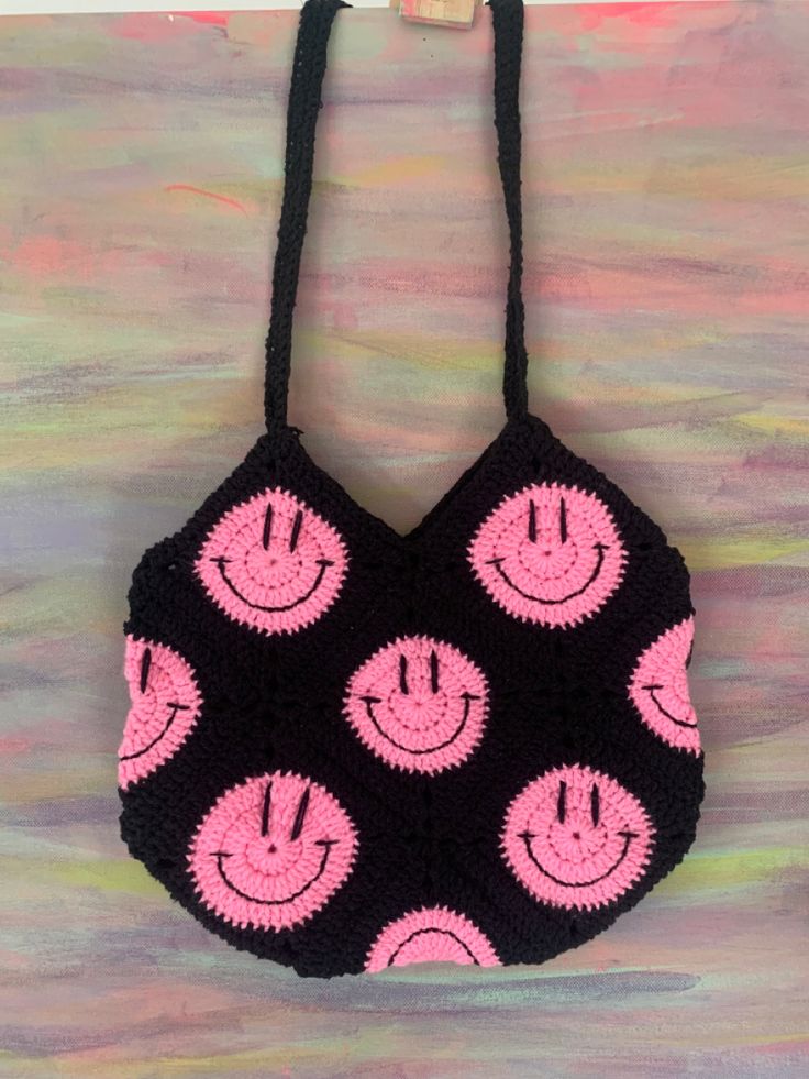 a crocheted black and pink bag with smiling faces on it's sides