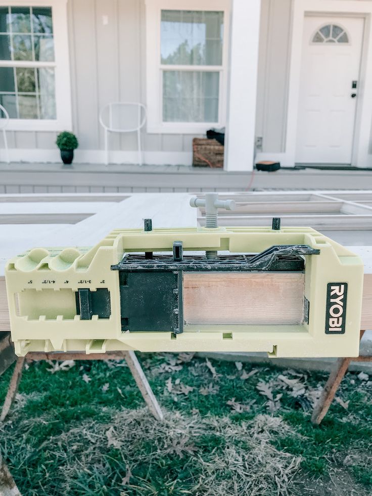 an electronic device sitting on top of a wooden table in front of a white building