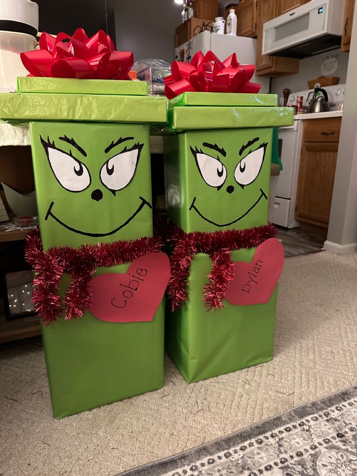 two green boxes with red bows and eyes on them sitting in the middle of a living room