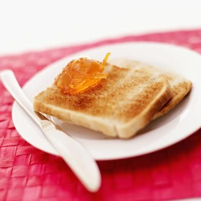 a white plate topped with two pieces of toast covered in orange marmalade syrup