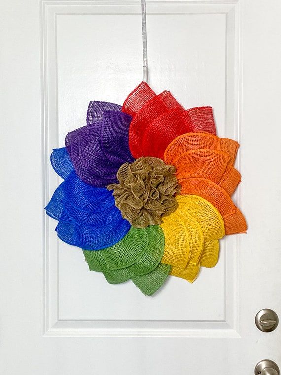 a rainbow colored wreath hanging on a white door