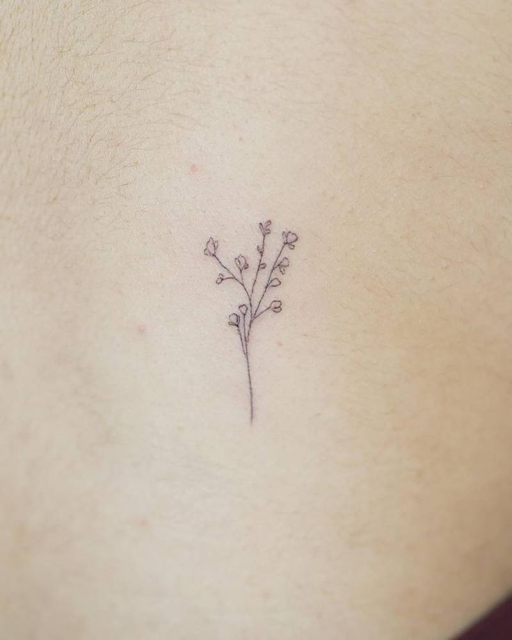 a small flower tattoo on the back of a woman's stomach