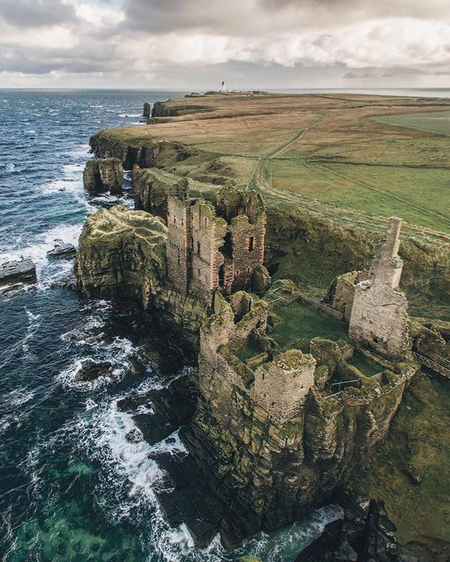 an aerial view of the cliffs and ocean with dark clouds in the sky over them