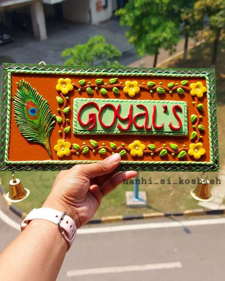 a hand holding up a sign that says goula's with a peacock on it