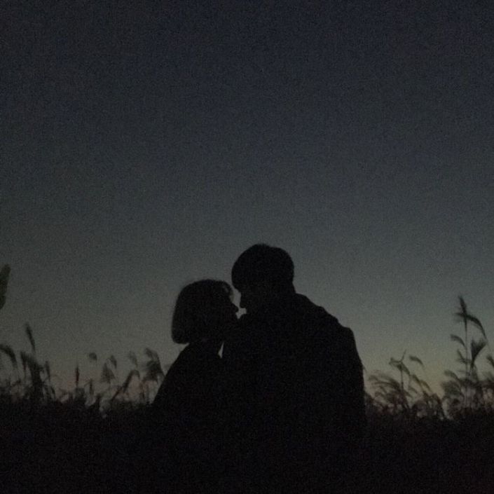 two people sitting in the grass at night