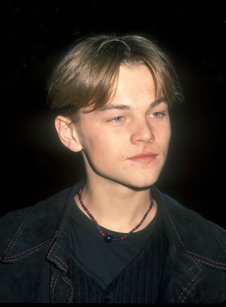 a young man wearing a black jacket and necklace