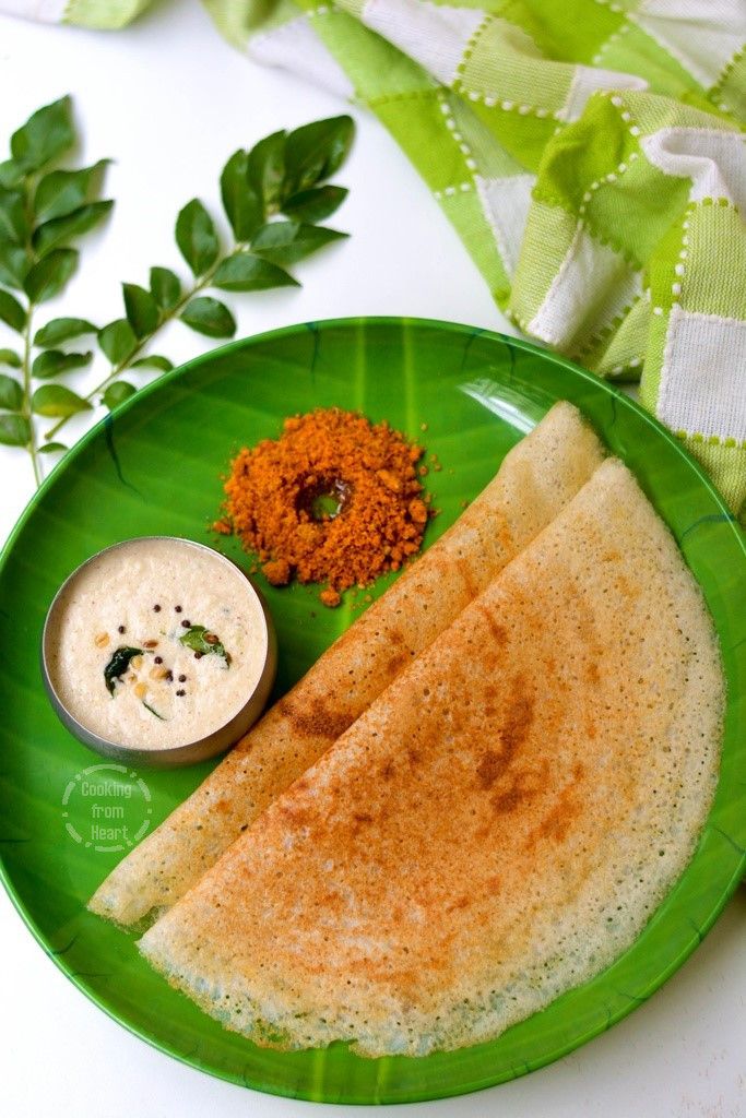 a green plate topped with two quesadillas next to a bowl of dip