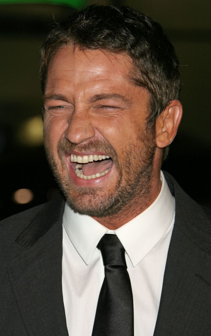 a close up of a person in a suit and tie smiling at something with his eyes closed