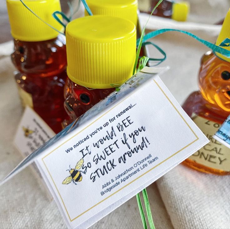 some honey bottles are sitting on a table with a sign that says it would bee so sweet if you stick it at them