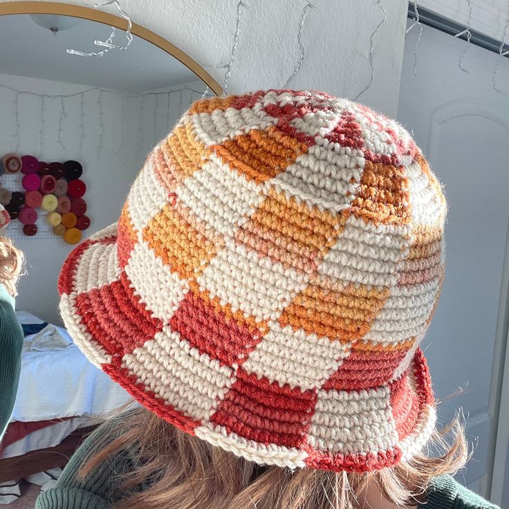 a woman wearing a crocheted hat in front of a mirror