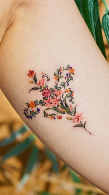 a woman's arm with flowers and leaves on the left side of her arm