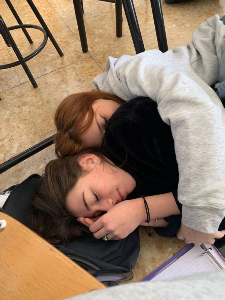 two people laying on the floor with their arms around each other and one person sleeping