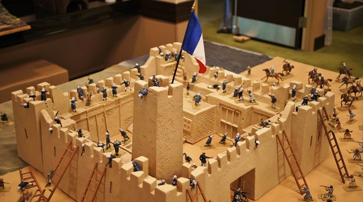 a model of a castle with people on it and a flag in the middle one