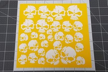 a yellow and white sticker with skulls on it