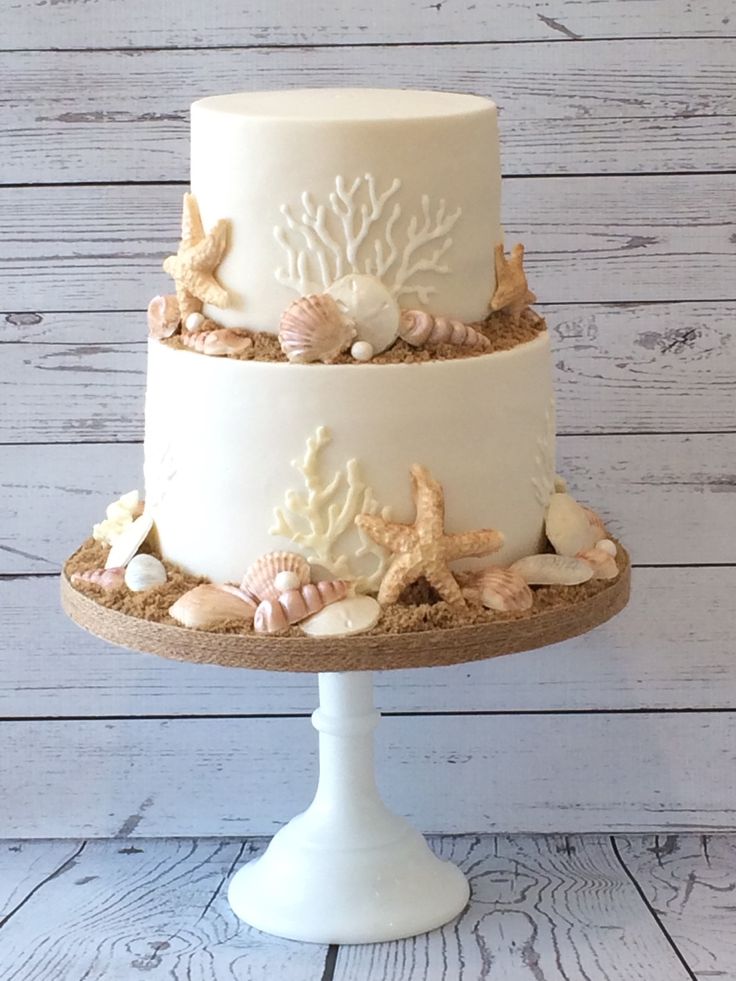 a three tiered cake decorated with seashells and starfish