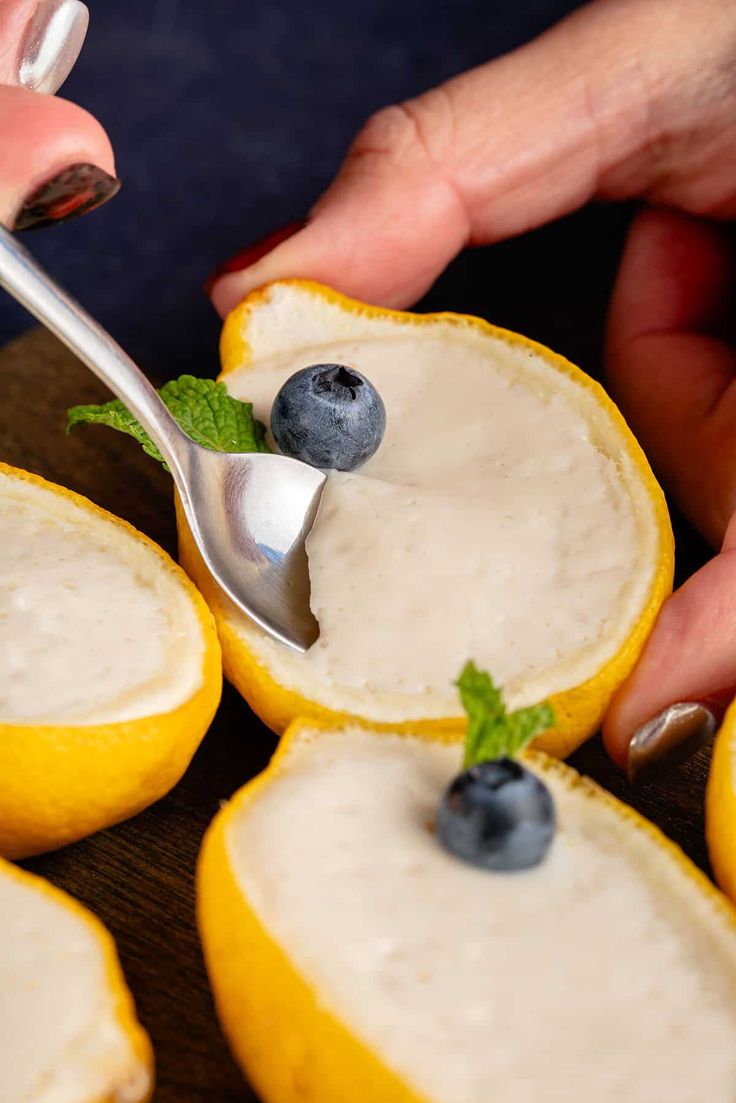 someone is spooning blueberries and lemons with yogurt sauce on them