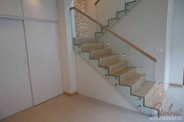 a staircase with glass railing and wooden handrails in an empty room next to a closet