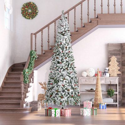 a decorated christmas tree sitting in the middle of a living room next to a staircase