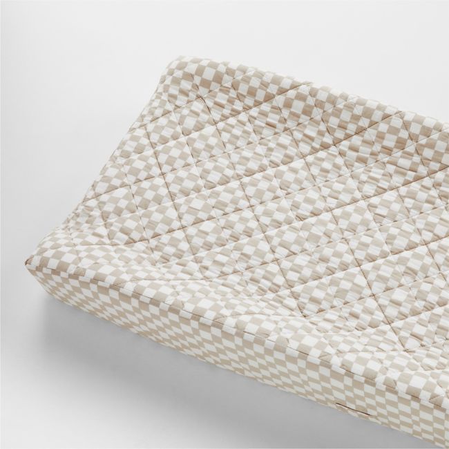 a white and beige checkered pillow on a white surface