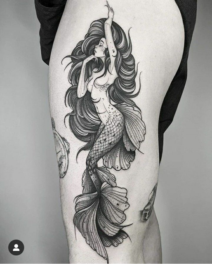 a woman with long hair and a fish tattoo on her thigh is shown in black and white